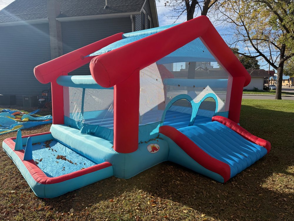 Red and blue house-shaped bounce house with a slide and a splash pool
