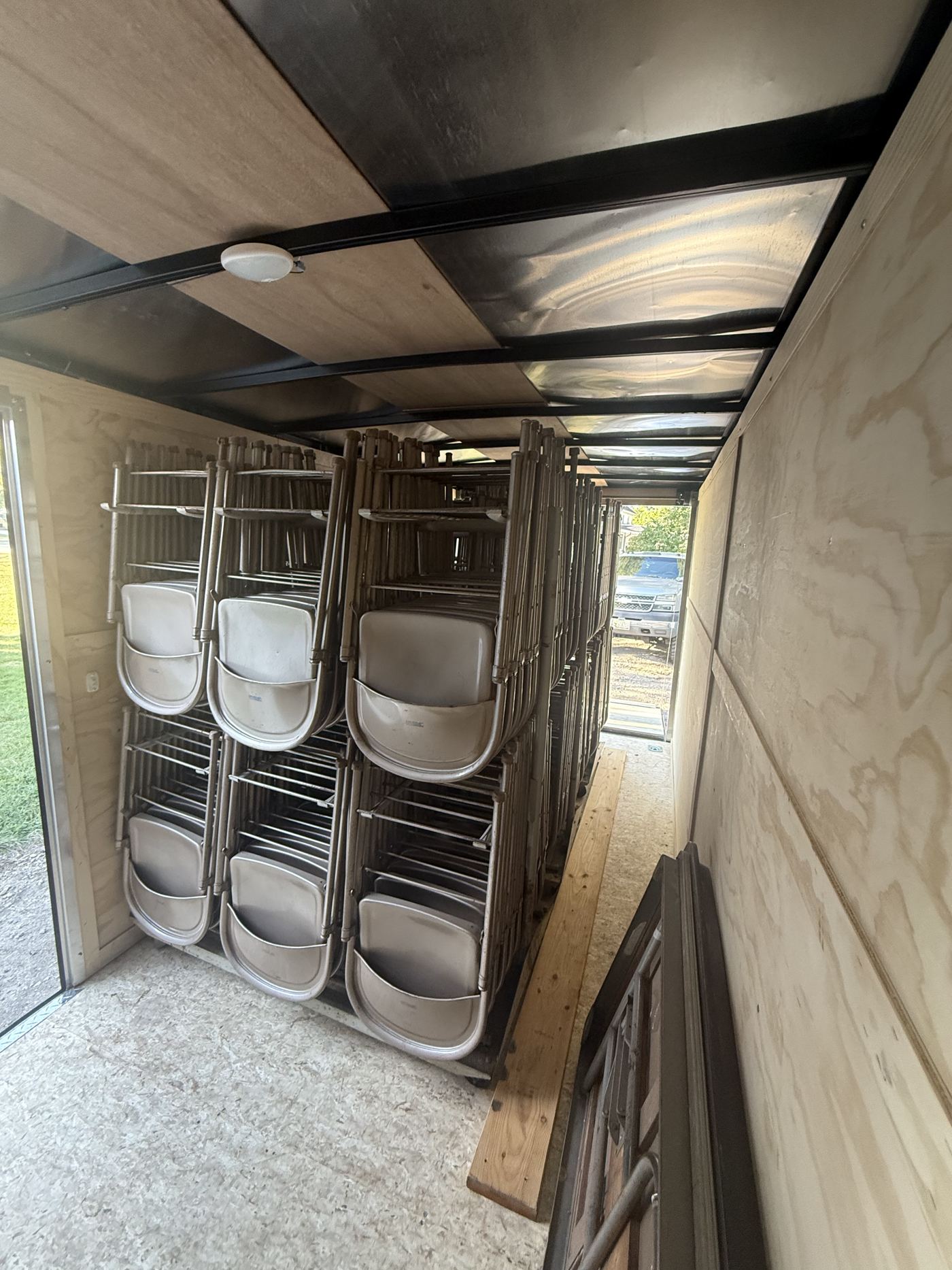 Folding chairs hung on racks inside the enclosed trailer, rear doors open