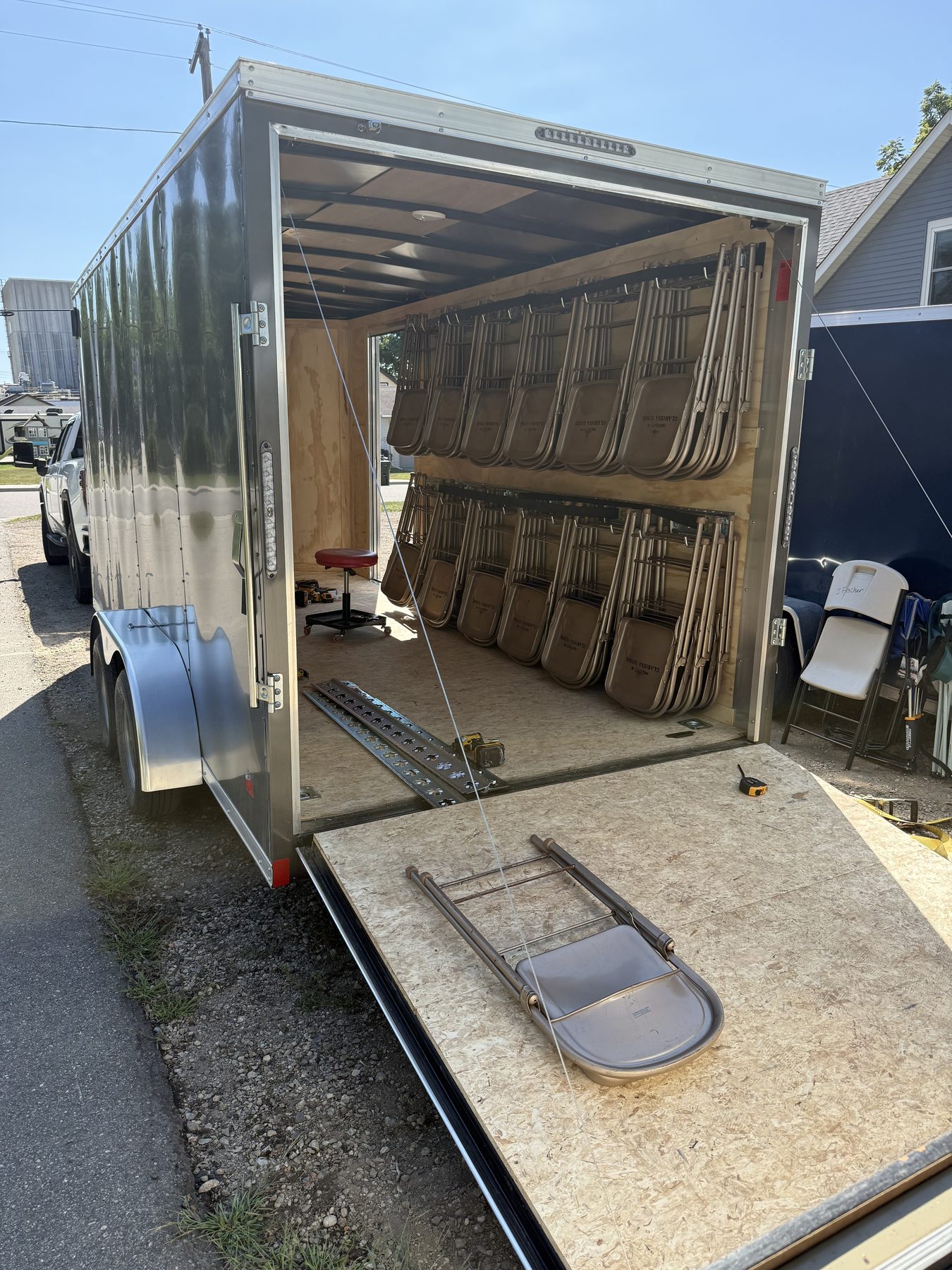 The enclosed Hitch and Host trailer parked in Albany with the ramp down and rear doors open, folding chairs loaded on racks inside